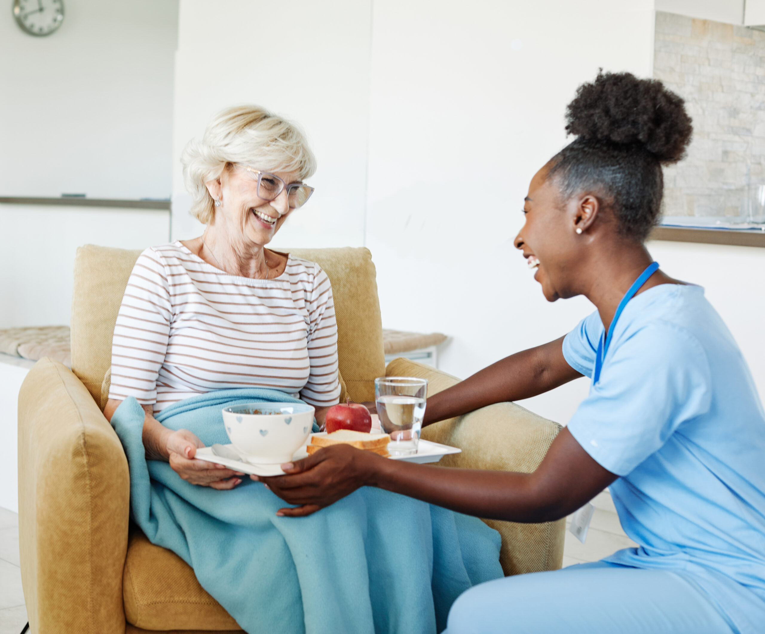 A Support Worker serving a meal to a seated older woman.